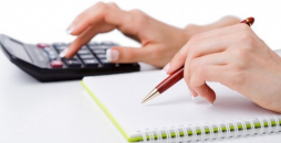 foto das mãos de uma pessoa usando um bloco de anotações e uma calculadora para representar como quitar o empréstimo pessoal