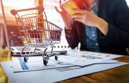 uma mulher fazendo compras pela internet através do celular com um cartão de crédito pré pago virtual