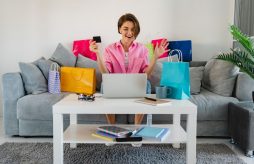 uma mulher sentada no sofá com diversas compras que foram feitas com as vantagens do cartão pré-pago