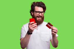 homem segurando um celular e um cartão de crédito para representar o texto sobre cartão de crédito com limite de 500 reais
