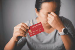 mulher com expressão de tristesa segurando um cartão de crédito consignado com dívida infinita
