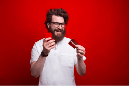 homem segurando um celular e um Cartão de crédito com limite garantido