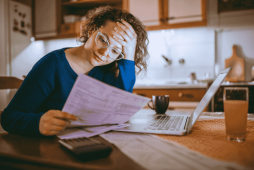 mulher olhando para conta em frente ao computador representando os bancos que aceitam pagamento de boleto com cartão de crédito