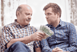 dois homens se olhando, um deles a emprestar dinheiro para parente