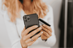 mulher com cartão e celular na mão fazendo compras para representar quando a fatura fecha pode comprar