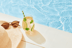 imagem de um óculos de sol, chapéu e bebida ao lado de uma piscina representando Como funciona a venda das férias
