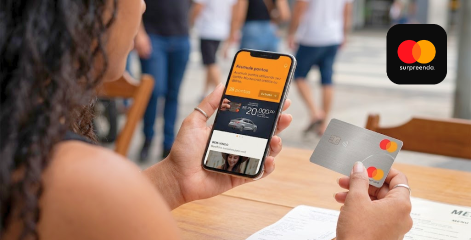 Mulher no app Mastercard Surpreenda e segurando cartão mastercard na outra mão